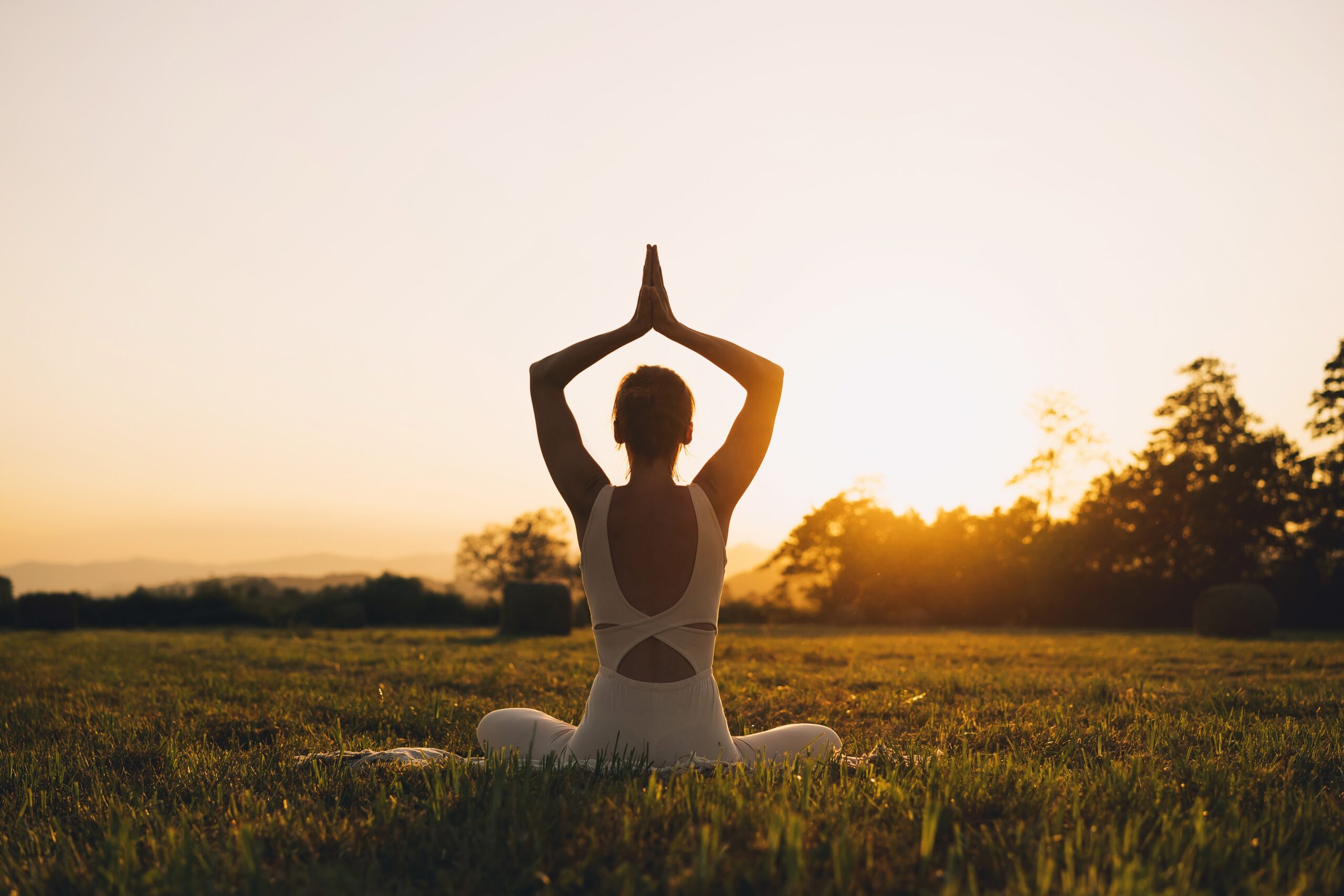 A woman practicing yoga outdoors at sunrise, symbolizing the connection between physical exercise, mental clarity, and improved brain function.