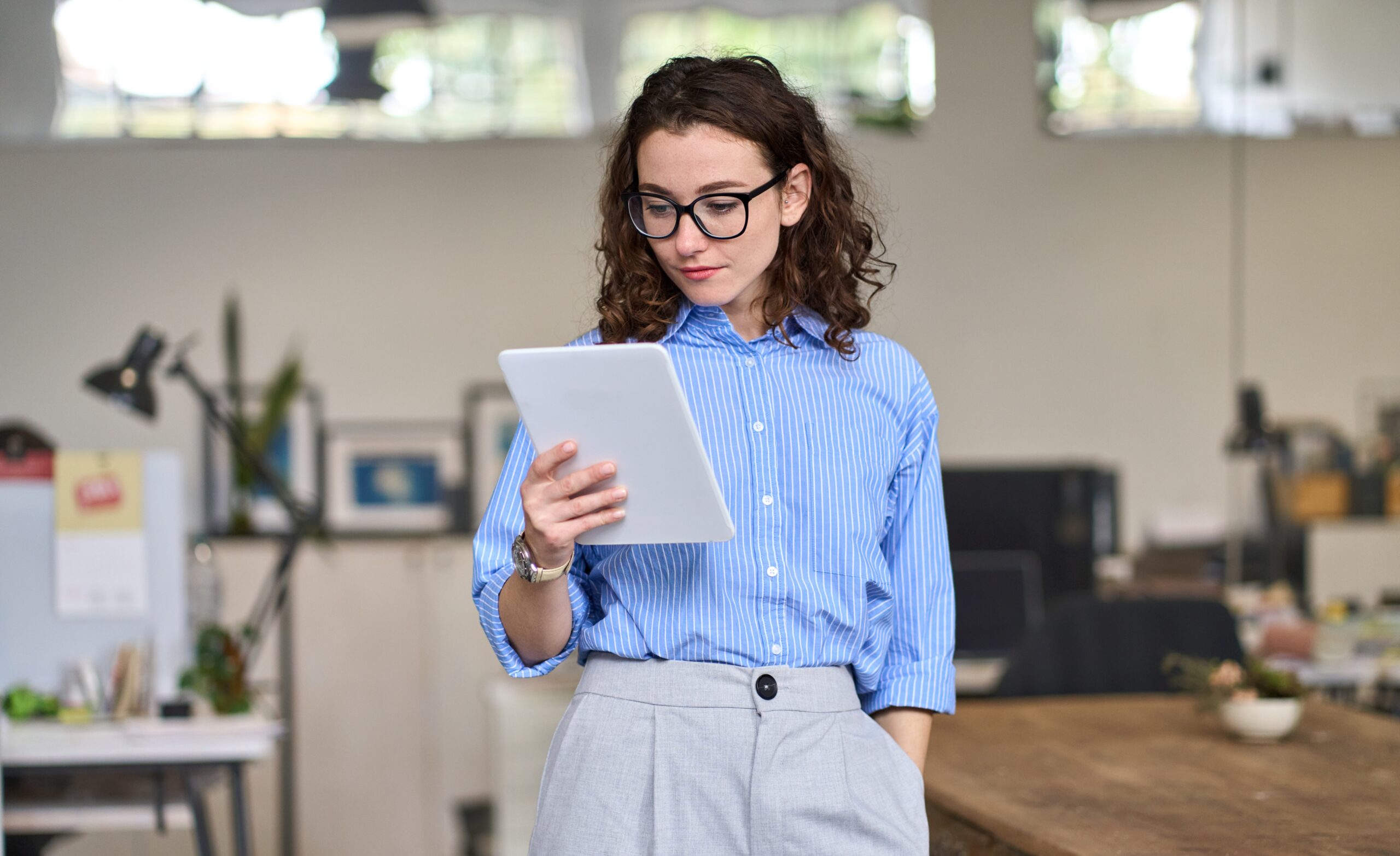 A professional woman reading from a tablet in a modern office, symbolizing the concept of speed reading and efficient information processing.