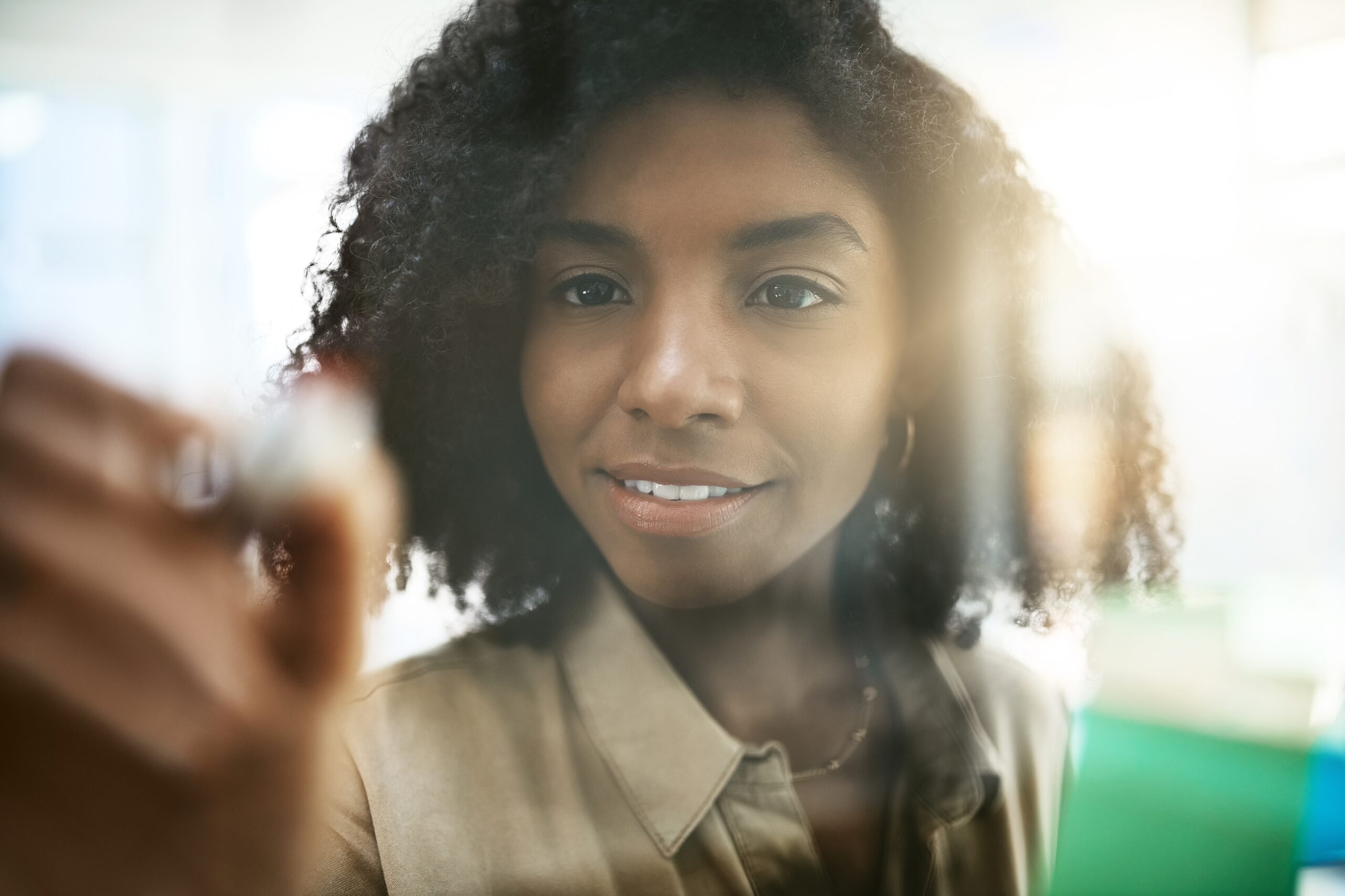 A smiling woman writing on a transparent board, symbolizing the use of visual tools like mind maps to organize and accelerate learning.